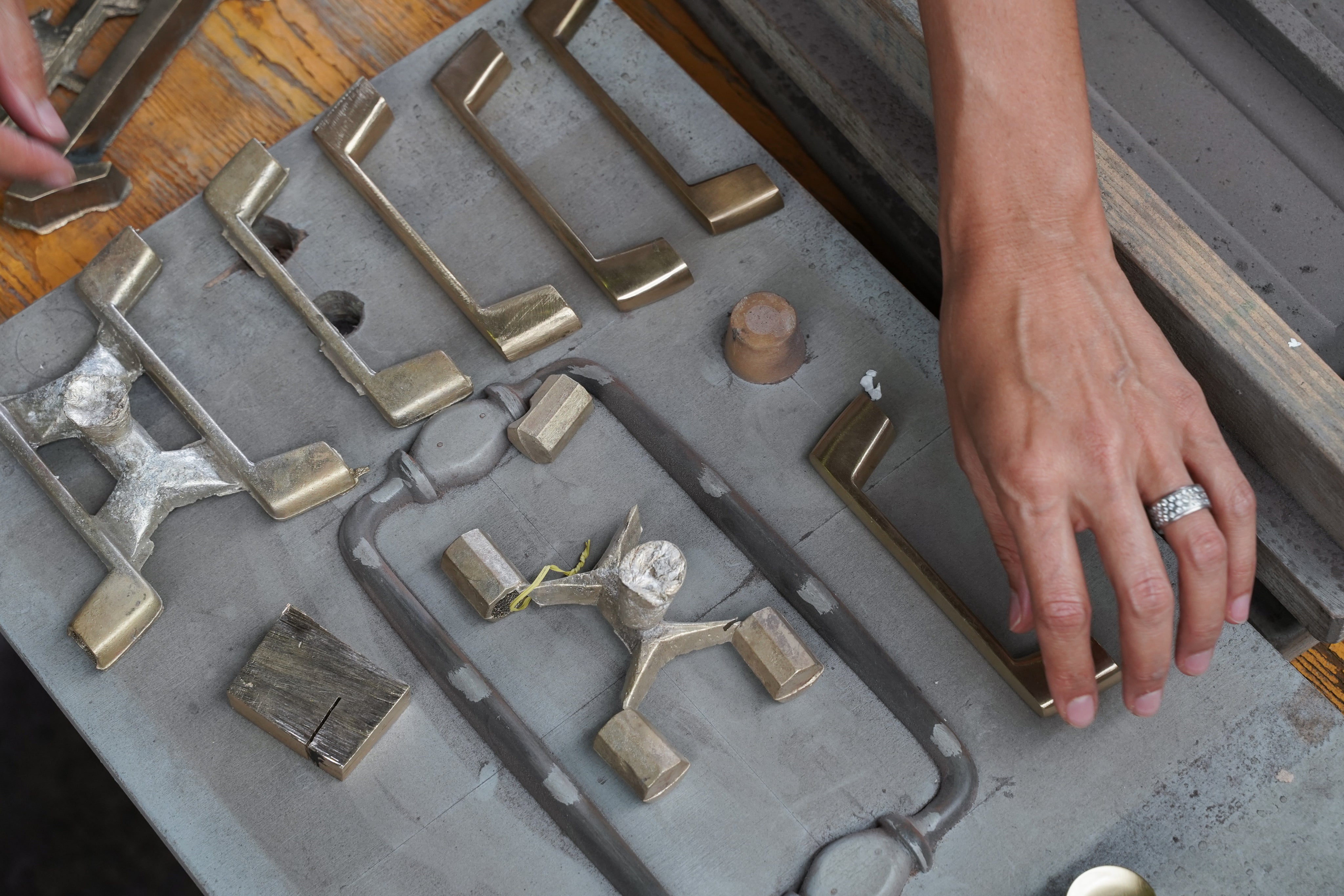 Metalworking process with metal pieces and a mold on a wooden surface.